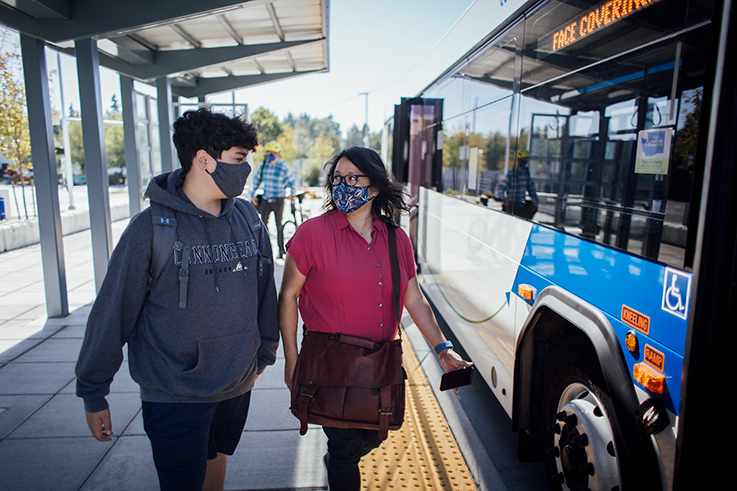 Woman and teenage boy wearing masks as they enter the Community Transit bus.